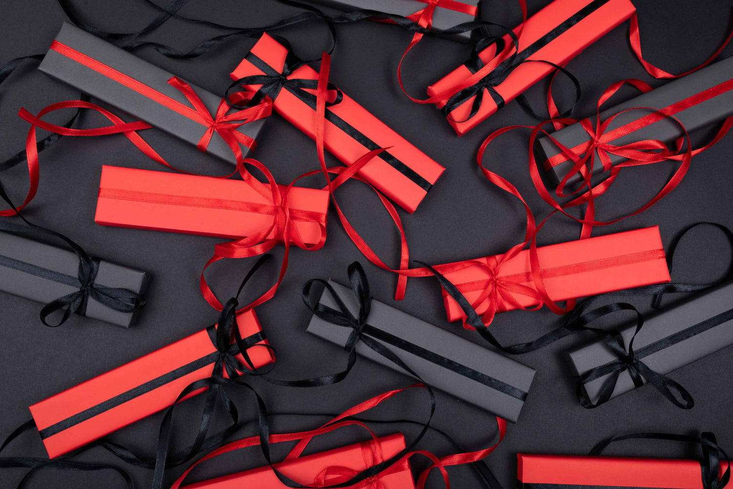 CuteBoxInc Background Image of Black and Red gifts with satin bows on black background. Photo by Tamanna Rumee