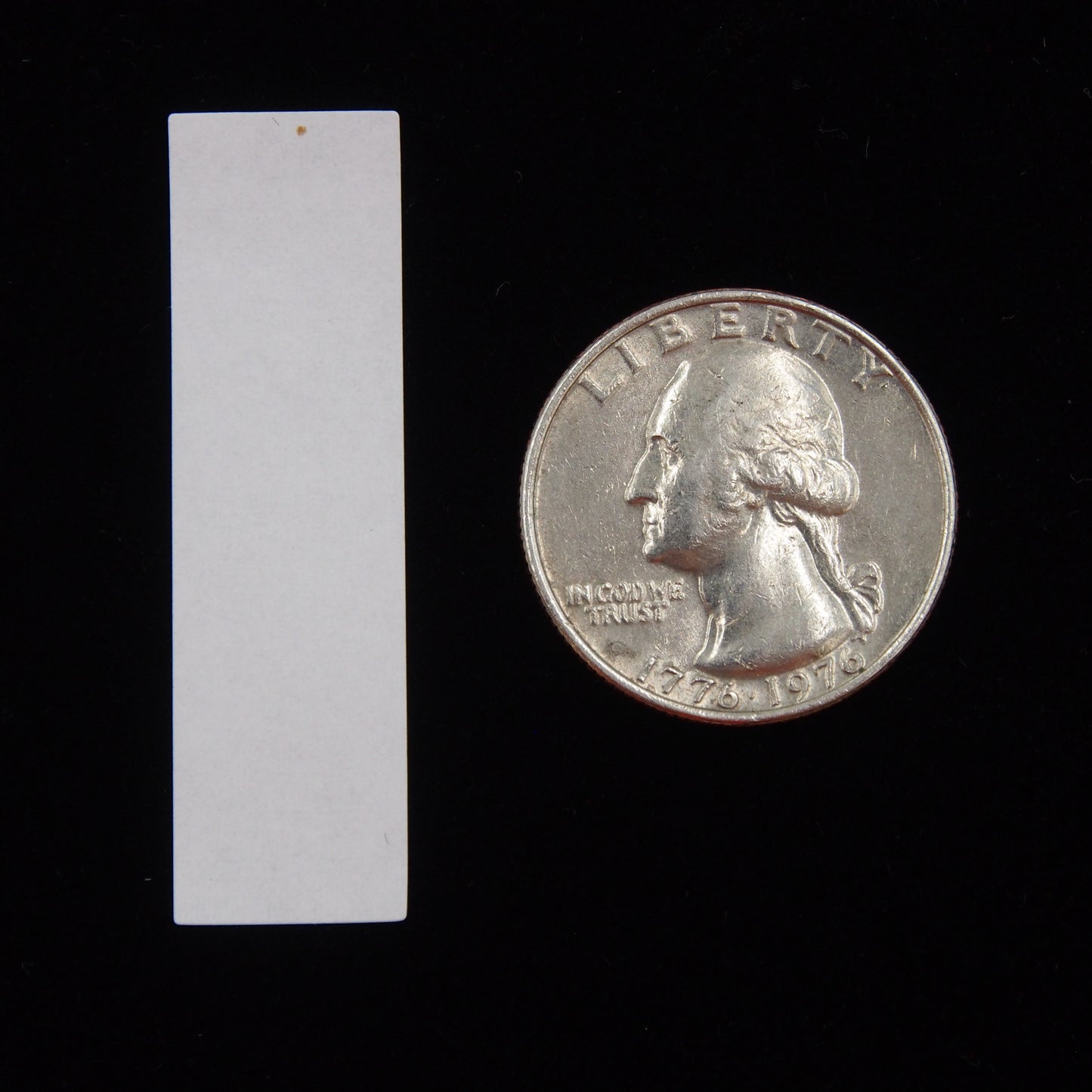 Vertical Rectangular Self Adhesive Plain Label - (1/2" x 1 3/4") next to a U.S. Quarter