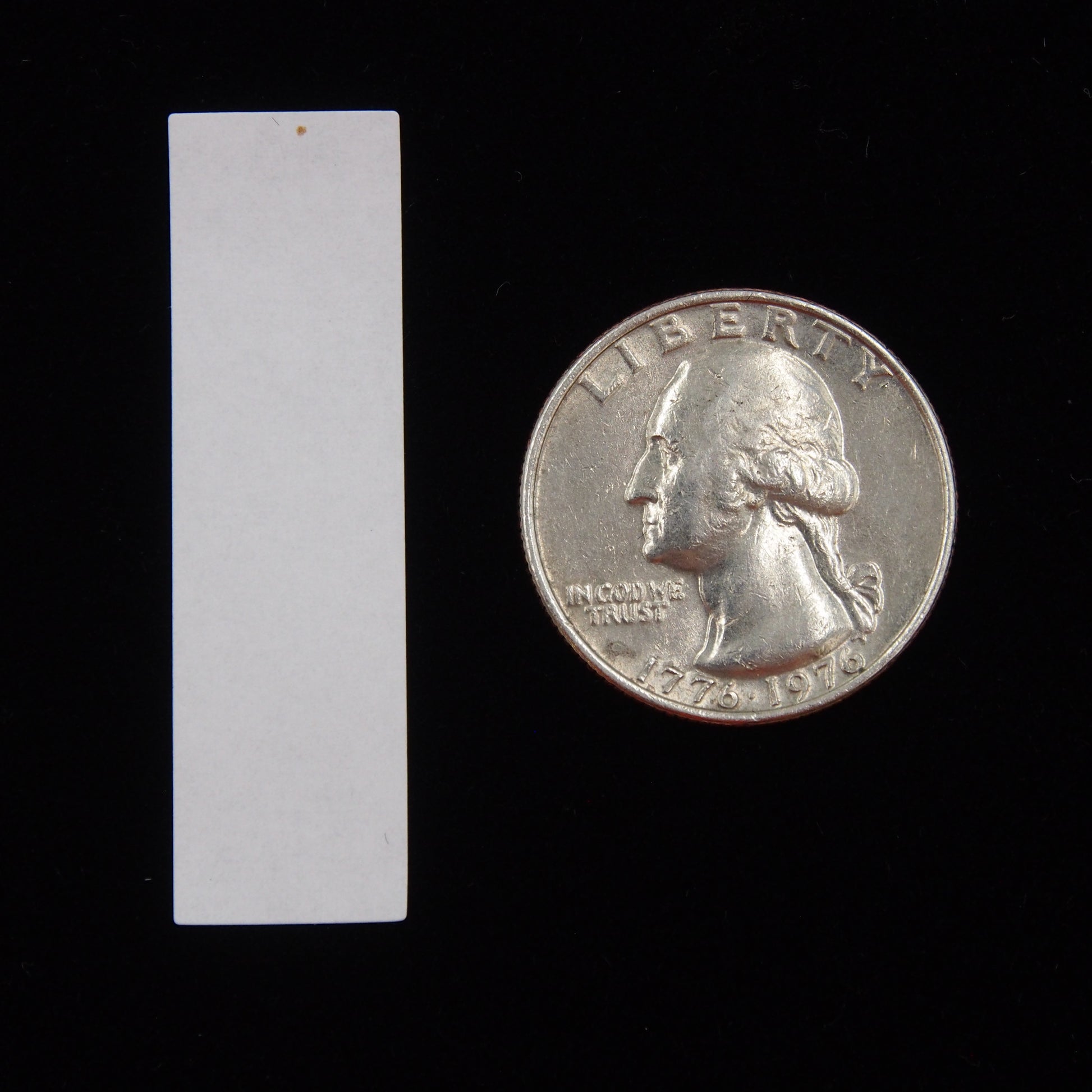 Vertical Rectangular Self Adhesive Plain Label - (1/2" x 1 3/4") next to a U.S. Quarter